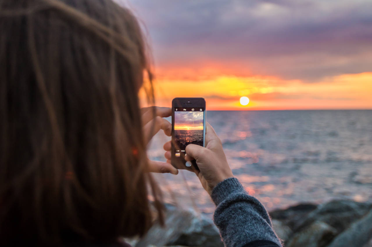 a girl taking a picture of sunset
