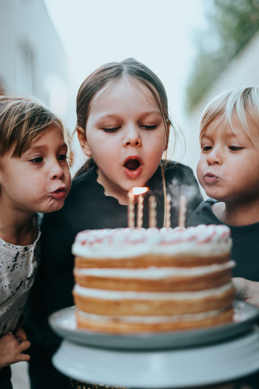 children blowing candles on a birthday cake